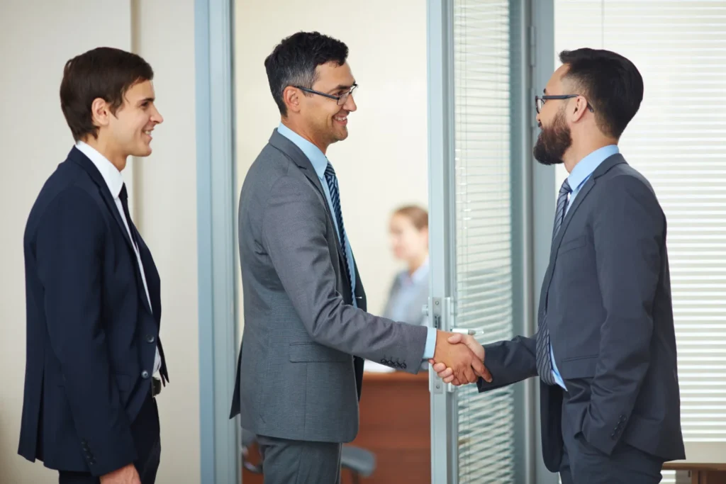 Real estate professionals shaking hands during a trusted referral introduction