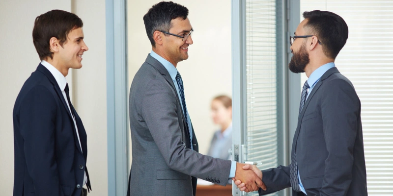 Real estate professionals shaking hands during a trusted referral introduction